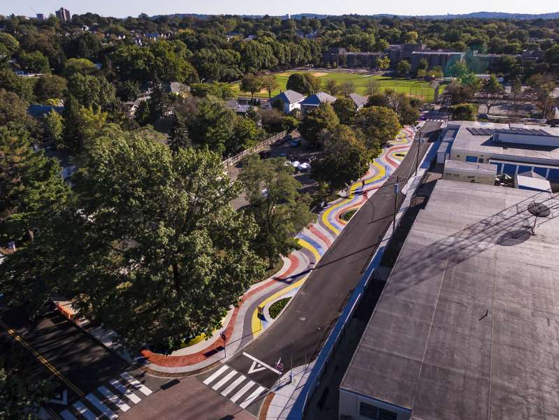 Aerial view of walk-able strip next to road that has been painted with waves of colors.