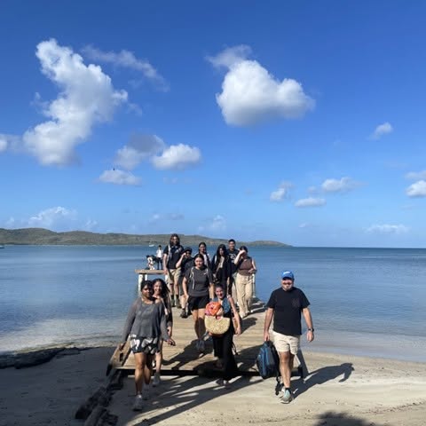 Group on dock in front of blue water and skies