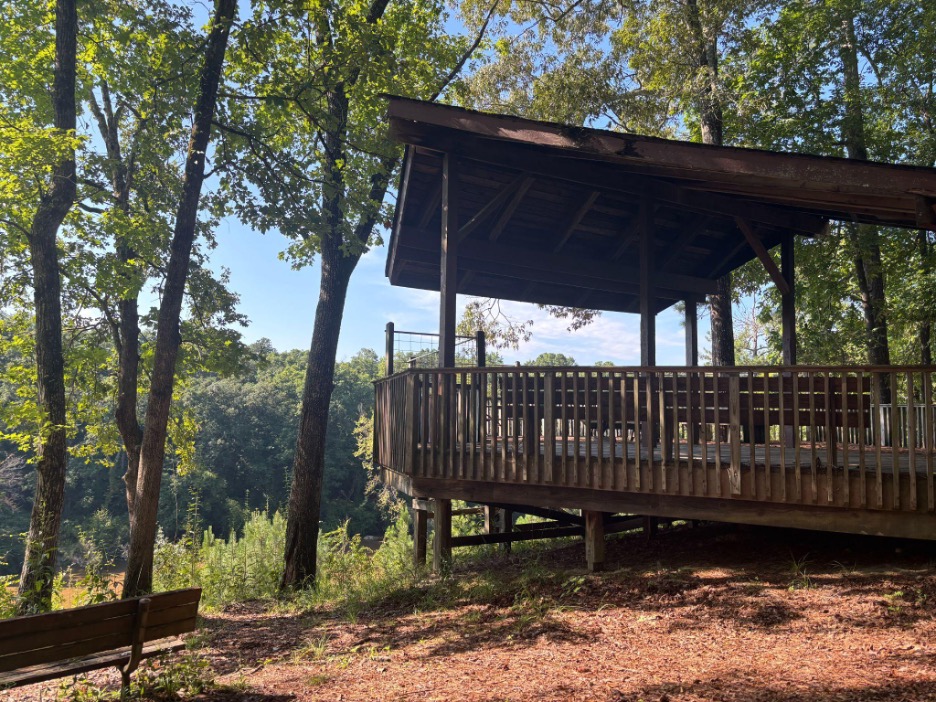 Wooden pavilion in wooded area.
